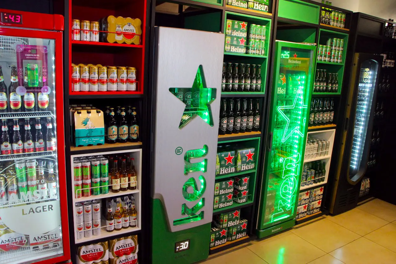 Corredor de gôndolas da loja com packs de cerveja e refrigerante